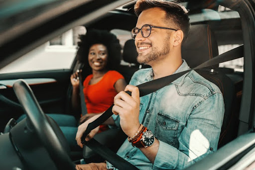 Young multiracial couple sitting in a car and fastening seat belts.